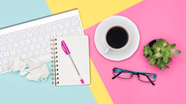 istock Creative flat lay photo of workspace desk. Top view office desk with notepad, wireless keyboard, succulent plant, coffee cup and glasses on pastel colored background. 1001366792