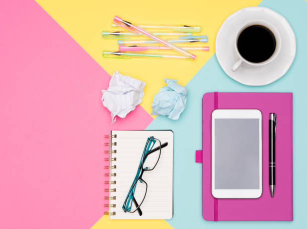 istock Office Desk Working Space Flat Lay. Top view photo of workspace with smartphone, coffee cup and open notepad on pastel background. Pastel color working desk. 1001366968