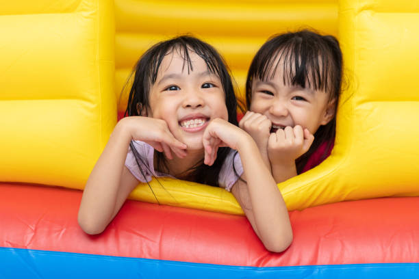 asian little chinese sisters playing at inflatable castle - inflatable child playground leisure games imagens e fotografias de stock