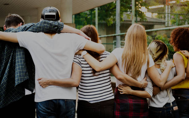 Smiling happy young adult friends arms around shoulder outdoors friendship and connection concept Smiling happy young adult friends arms around shoulder outdoors friendship and connection concept friendship support stock pictures, royalty-free photos & images