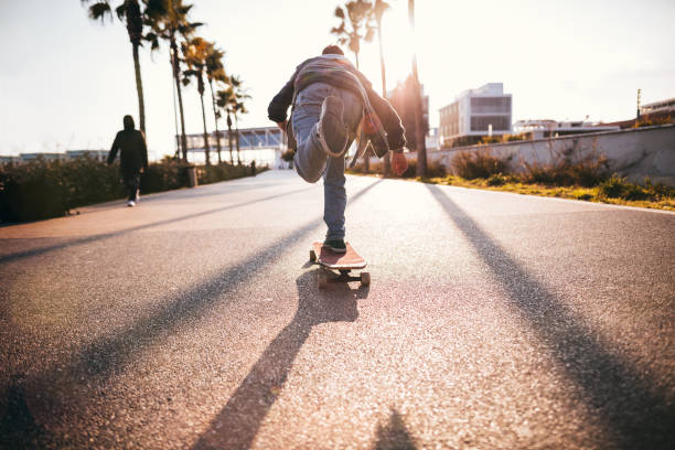Cool teenage boy skateboarding in urban park as a hobby stock photo