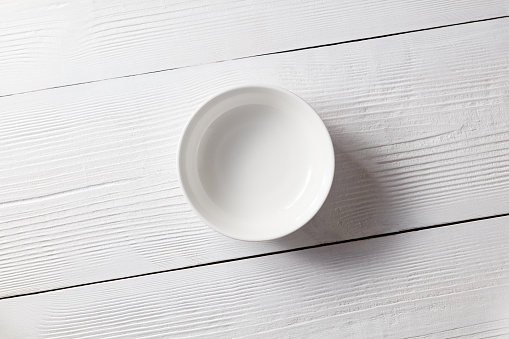 White ceramic empty plate on a white wooden table with copy space.
