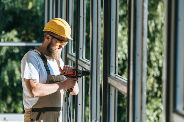 istock side view of builder in hardhat and protective googles installing windows by drill at construction site 1001383130