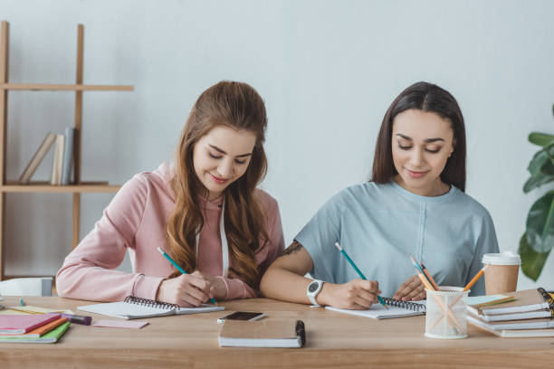 istock multiethnic girls studying together and writing in copybooks at table 1001383258