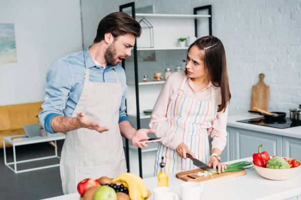 istock irritated boyfriend gesturing while girlfriend cutting vegetables in kitchen 1001385820