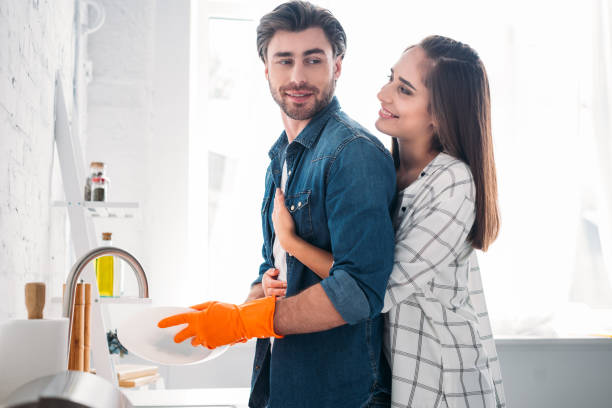 istock boyfriend washing dishes and girlfriend hugging him in kitchen 1001385830