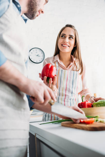 istock boyfriend cutting vegetables and girlfriend giving bell pepper in kitchen 1001386004