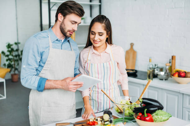 istock couple looking at tablet with recipe while cooking in kitchen 1001389888