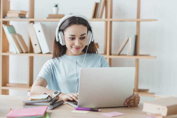 istock brunette female student studying with laptop and headphones 1001389946