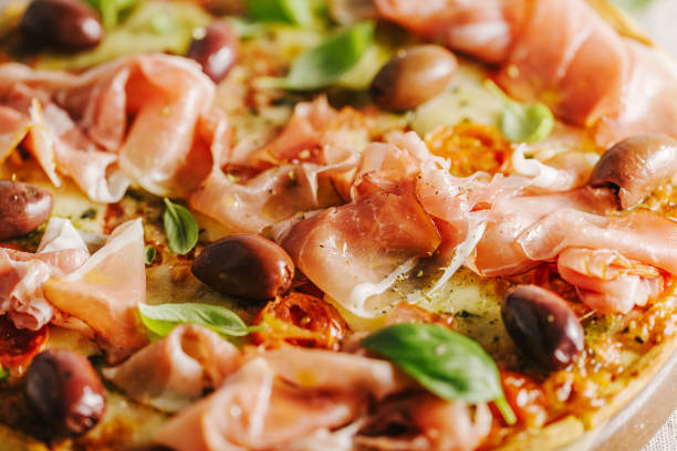 Closeup of appetizing classic traditional italian pizza with cheese, ham and vegetables on rustic textile. View from above