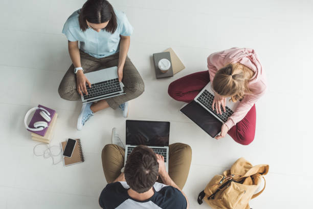 istock overhead view of students studying with laptops on floor 1001396352