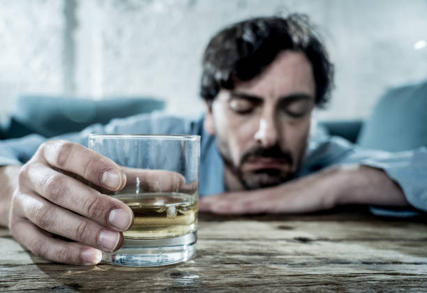 istock drunk alcoholic lain business man drinking whiskey from the bottle and glass depressed wasted and sad at home couch in alcohol abuse and alcoholism concept 1001401310