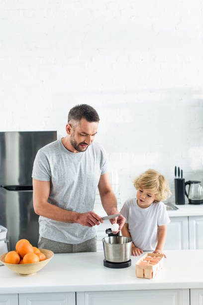 istock man with son breaking egg by knife into bowl at kitchen 1001401610