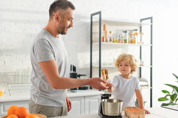 istock boy giving egg to father near tabletop at kitchen 1001401712