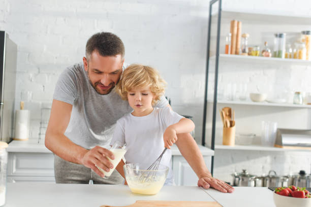 istock little boy whisking dough while his father pouring milk into bowl at kitchen 1001401780