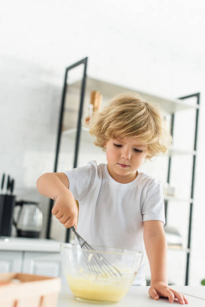istock concentrated little boy making dough by whisk on table at kitchen 1001401798