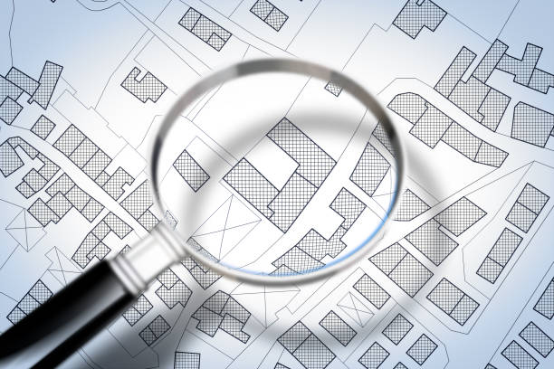 istock Imaginary cadastral map of territory with buildings and roads through magnifying glass 1001402060