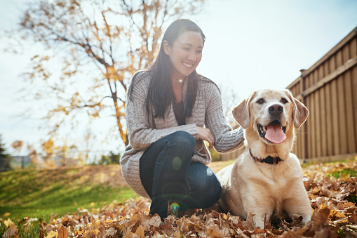 Shot of an attractive young woman having fun with her dog on an autumn day in a garden