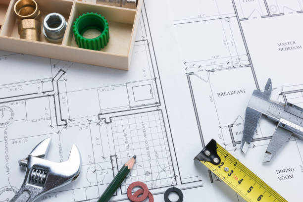 istock Spanner, Pencil, Measuring Tools and Plumbing Parts on Building Plan 1001404976
