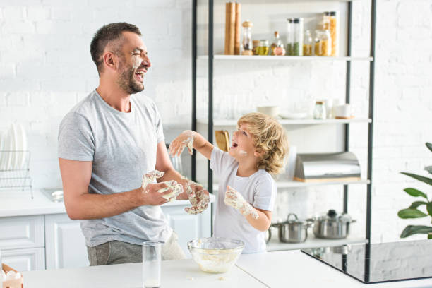 istock smiling father and son get covering by dough and having fun at kitchen 1001405410