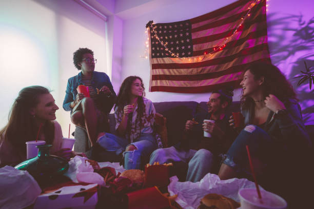 Young multi-ethnic friends relaxing at home and eating fast food Happy multi-ethnic teenage friends hanging out at home and eating fast food together college dorm party stock pictures, royalty-free photos & images
