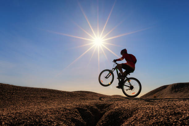 Cyclist riding mountain bike on the rocky trail at sunset.