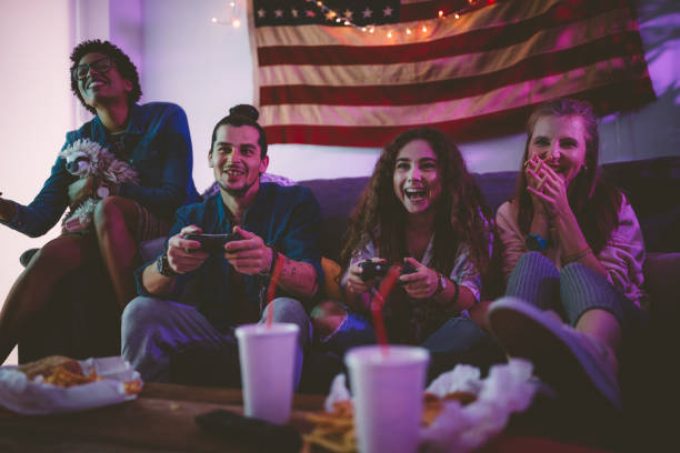 młodzi wieloetni przyjaciele jedzący fast foody i grający w gry wideo - adolescence flag university people zdjęcia i obrazy z banku zdjęć