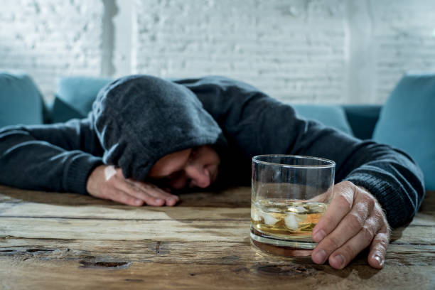 istock drunk alcoholic unemployed man drinking whiskey from the glass and bottle depressed wasted and sad at home couch in alcohol abuse and alcoholism concept 1001408730