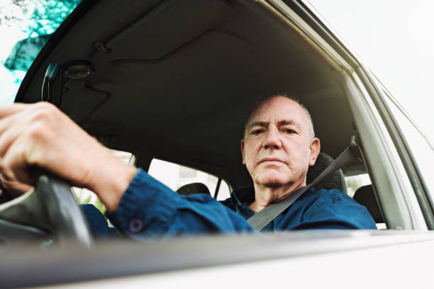 istock Senior man confidently driving car looks at camera 1001408900