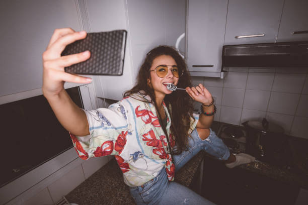 Young funky woman with lollipop taking selfies at home Young funky teenage girl eating lollipop and taking selfies for social media on smartphone alternative lifestyle photos stock pictures, royalty-free photos & images
