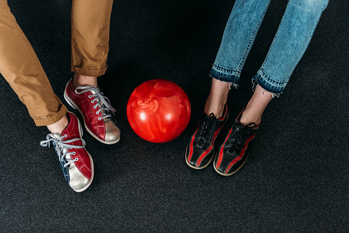 cropped shot of couple in rental bowling shoes with ball