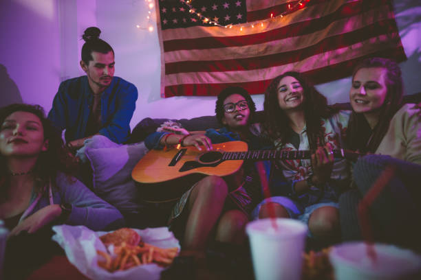 Happy multi-ethnic friends relaxing at home and playing the guitar