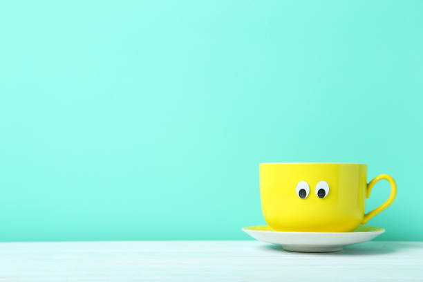 istock Yellow cup with googly eyes on a green background 1001414284