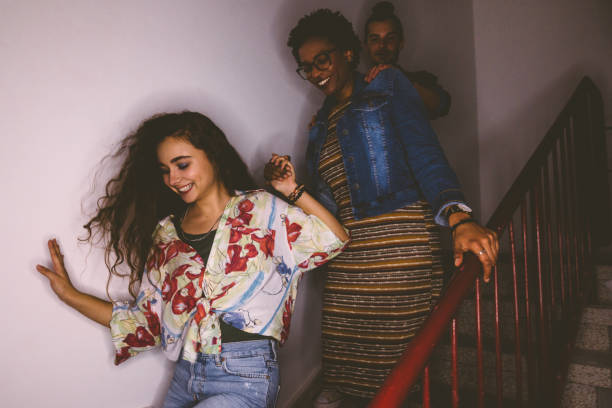 Happy multi-ethnic mischievous teenagers running down staircase Multi-ethnic teenage friends sneaking out house and running down staircase after mischief college dorm party stock pictures, royalty-free photos & images