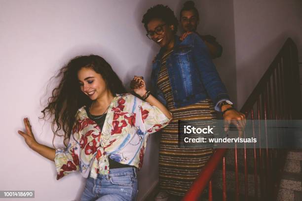 Happy Multiethnic Mischievous Teenagers Running Down Staircase Stock Photo - Download Image Now