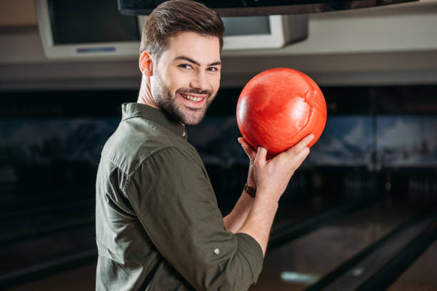 istock smiling young man holding bowling ball and looking at camera 1001422306