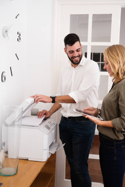 istock Man at a photo copier and woman holding tablet pc 1001423680