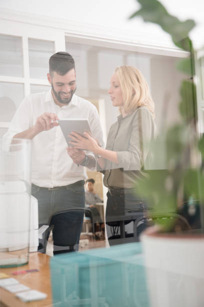 istock Man and woman smiling as she holds a pc tablet 1001423810
