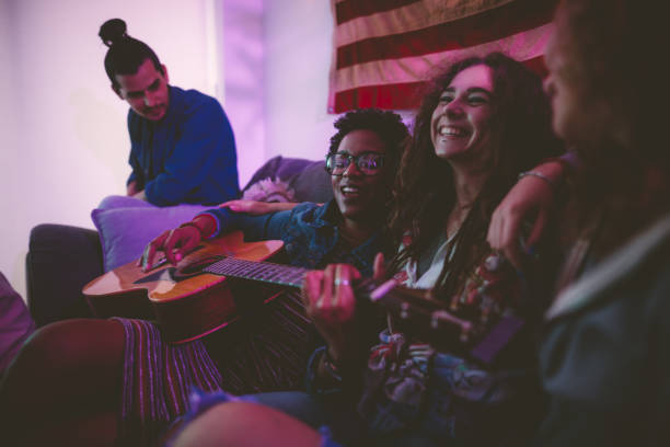 istock Multi-ethnic hipster friends playing the guitar and singing at home 1001423842