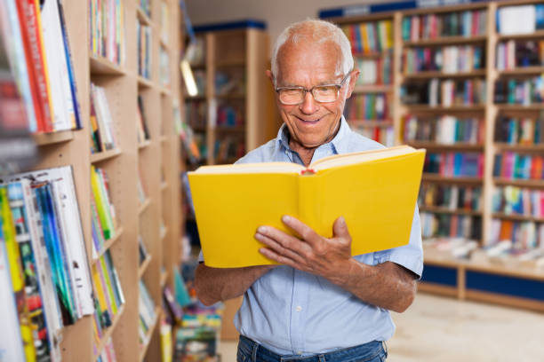 istock Older man reader browsing inside of books in bookshop 1001426780
