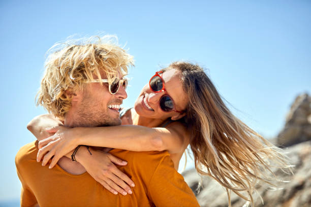 istock Man piggybacking girlfriend at beach in summer 1001427984