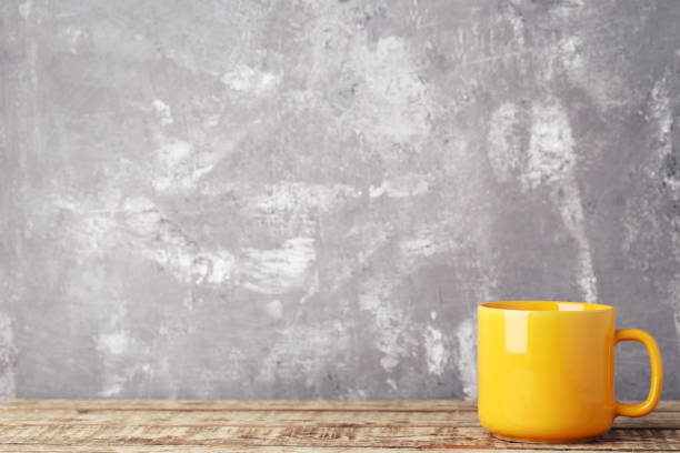 istock Yellow cup on wooden table 1001428188