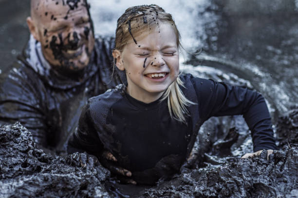istock Father and daughter having sporty fun at a public mud run obstacle course 1001434030