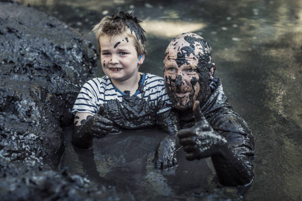 istock Father and son having sporty fun at a public mud run obstacle course 1001434262
