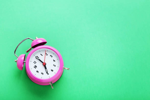 istock Pink alarm clock on the green background 1001434274