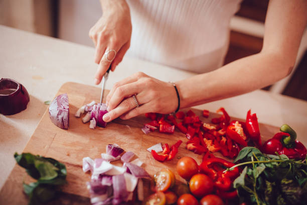 femme coupe oignons et légumes sur une planche à découper - mediterranean diet photos et images de collection