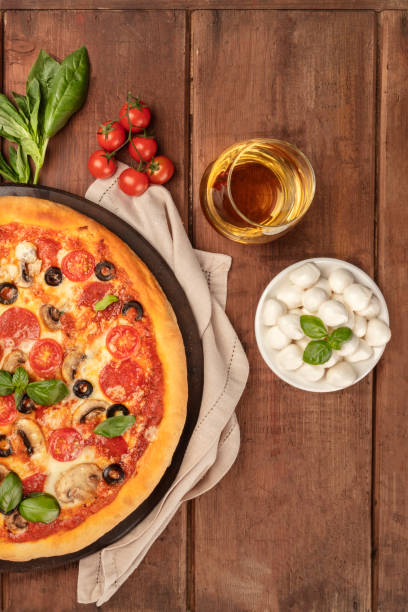 istock Pepperoni pizza closeup with white wine, ingredients, and place for text 1001469588