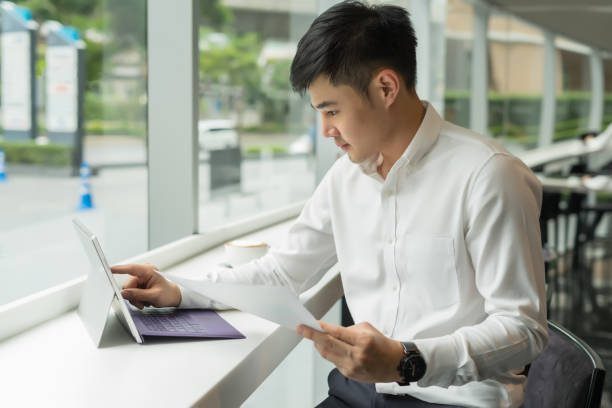 Handsome Asia businessman using laptop and analysis graph visualization at coffee shop
