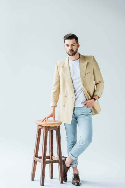 istock Fashionable confident man leaning on stool on white background 1001473264