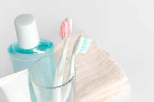 zahnbürsten, zahnpasta, spülen und handtuch auf weißem hintergrund. zahnmedizinische und medizinische konzept. kostenloses exemplar raum. - toothbrush pink turquoise blue stock-fotos und bilder